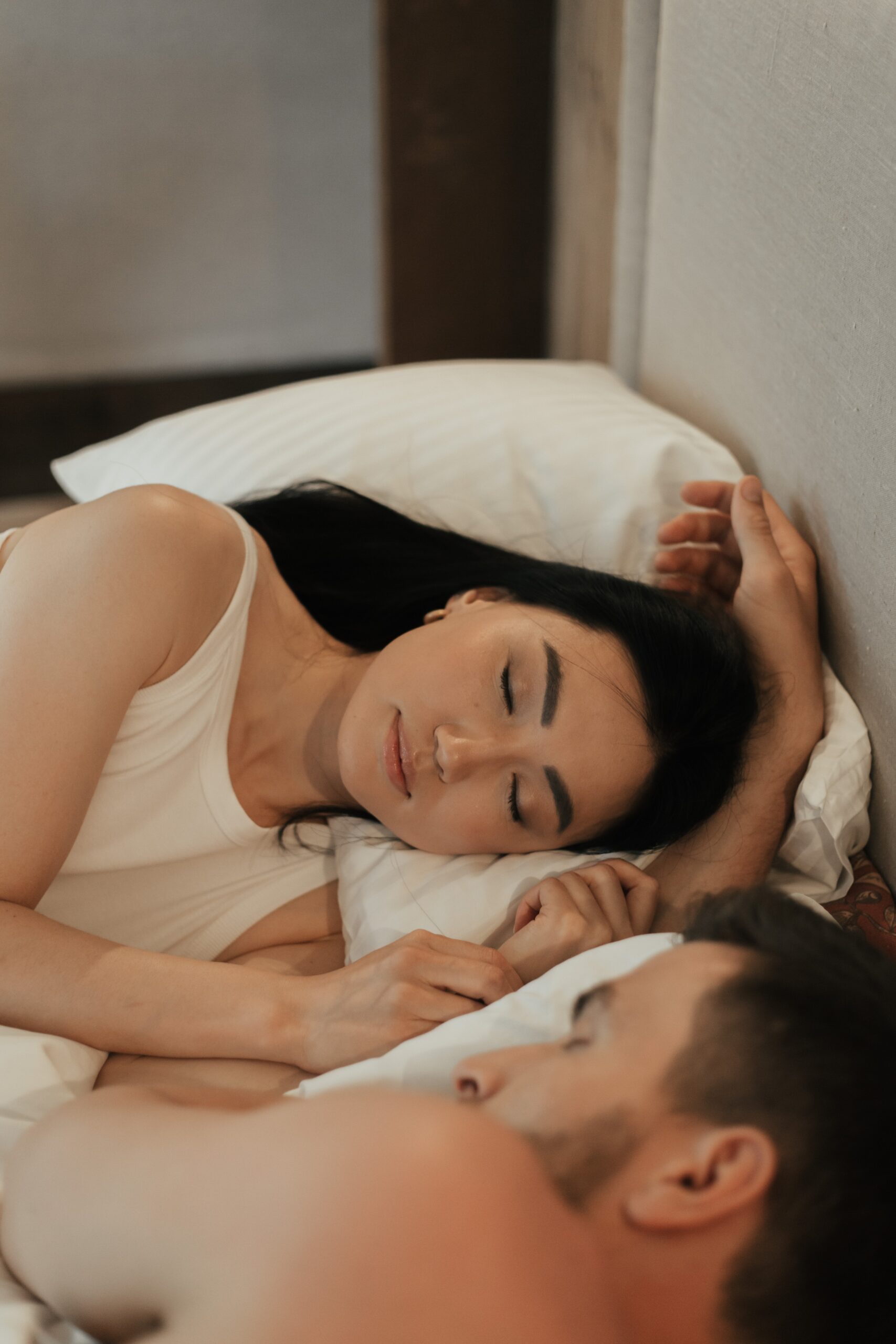 woman and man lying in bed next to each other with eyes closed